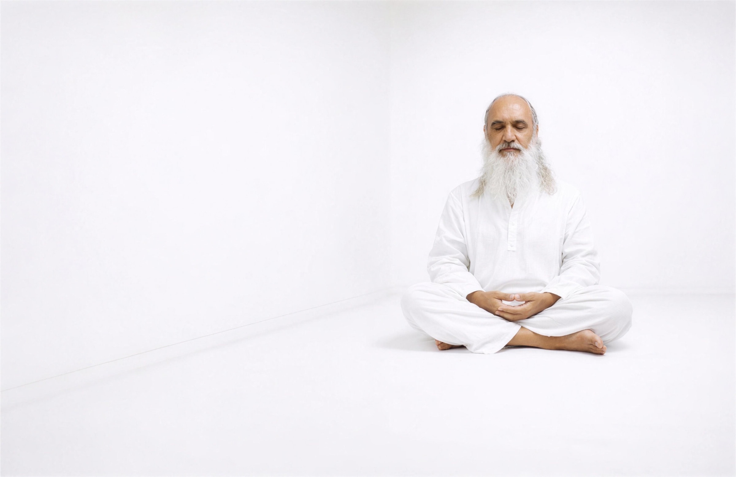 Sri Prem Baba seated in meditation in a bright white room